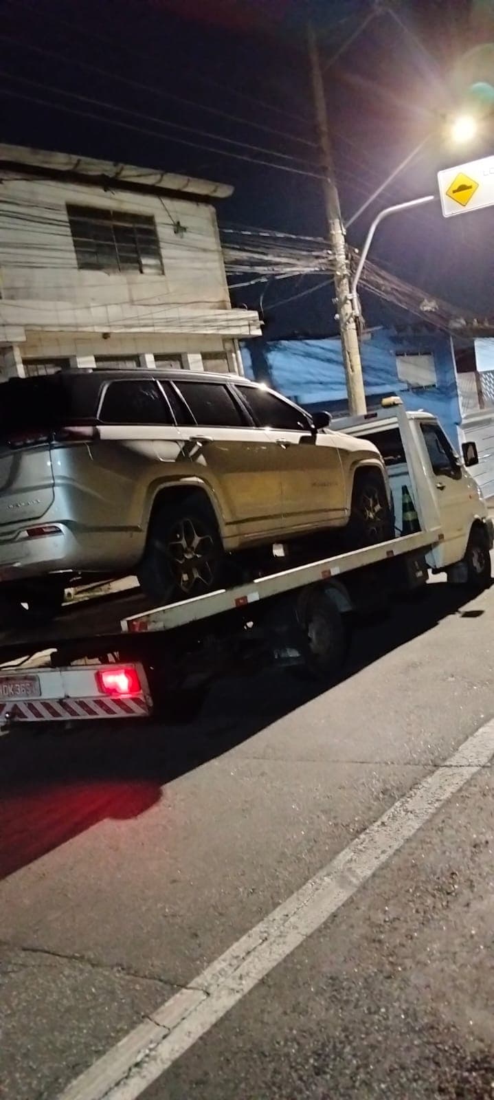 Guincho plataforma transportando um utilitário durante a noite